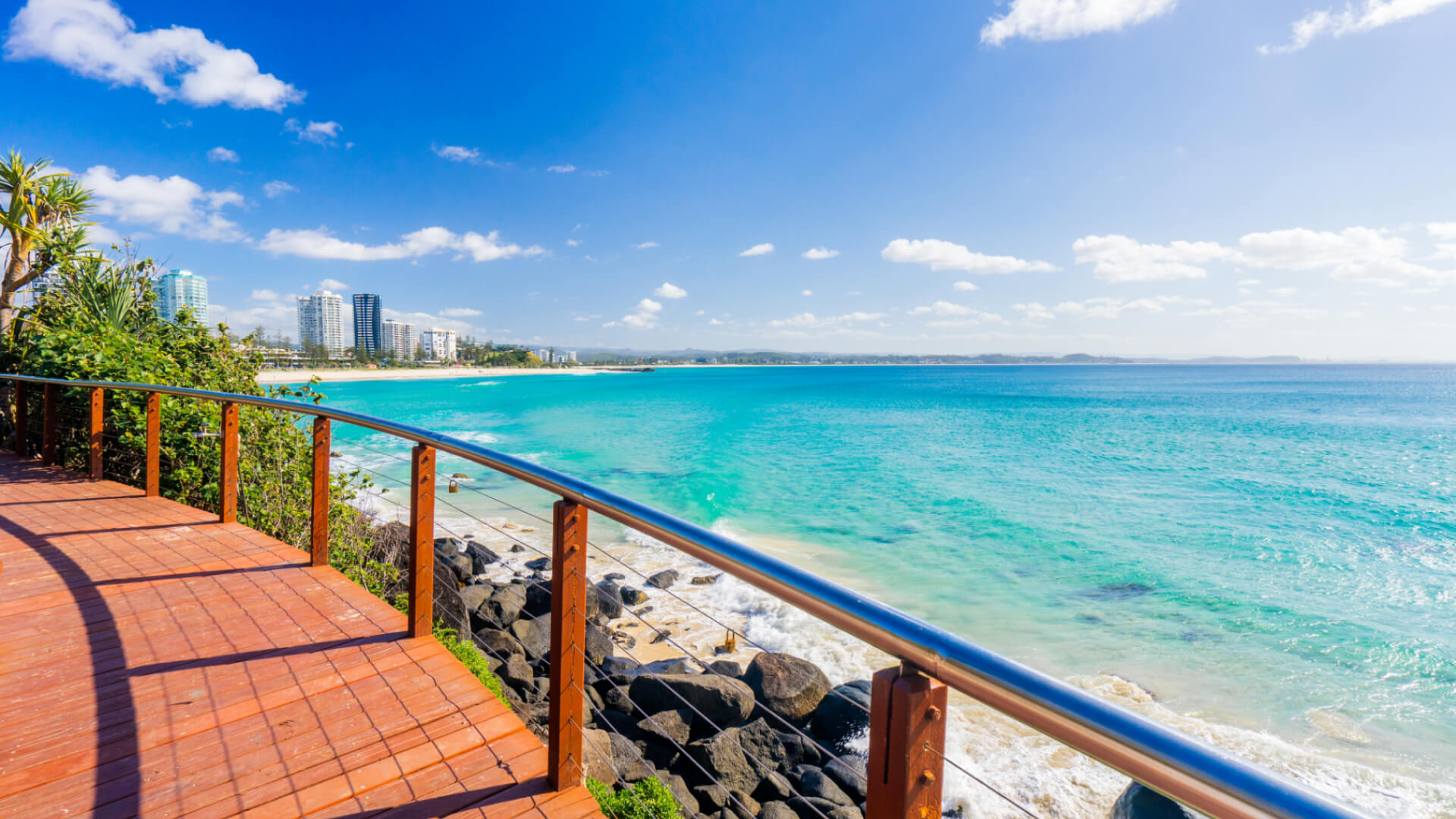 Scenic view from the Snapper Rocks boardwalk overlooking turquoise water and Coolangatta Beach on a sunny day.