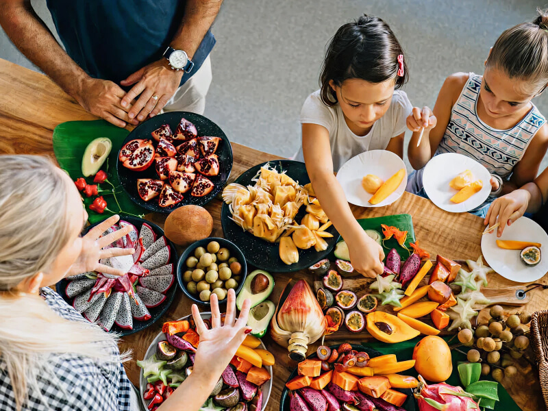 Family sampling a colorful spread of tropical fruits during a local food experience or market tour.