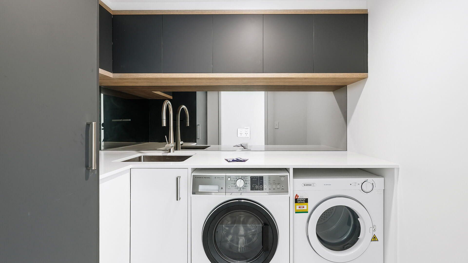 Internal laundry in the Deluxe 3 Bedroom Ocean View Apartment at ULTIQA Points North, featuring a washer, dryer, sink, and contemporary cabinetry.