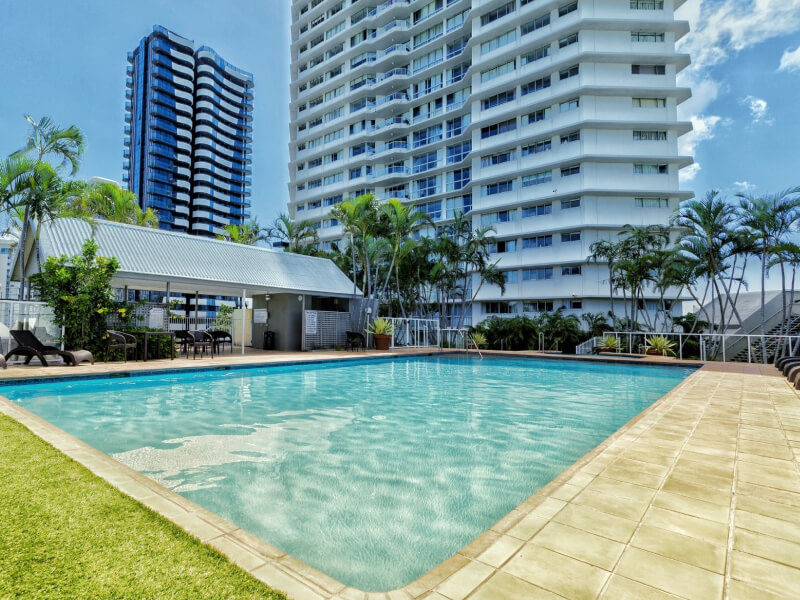 Outdoor pool area at ULTIQA Points North surrounded by palm trees and sun loungers.