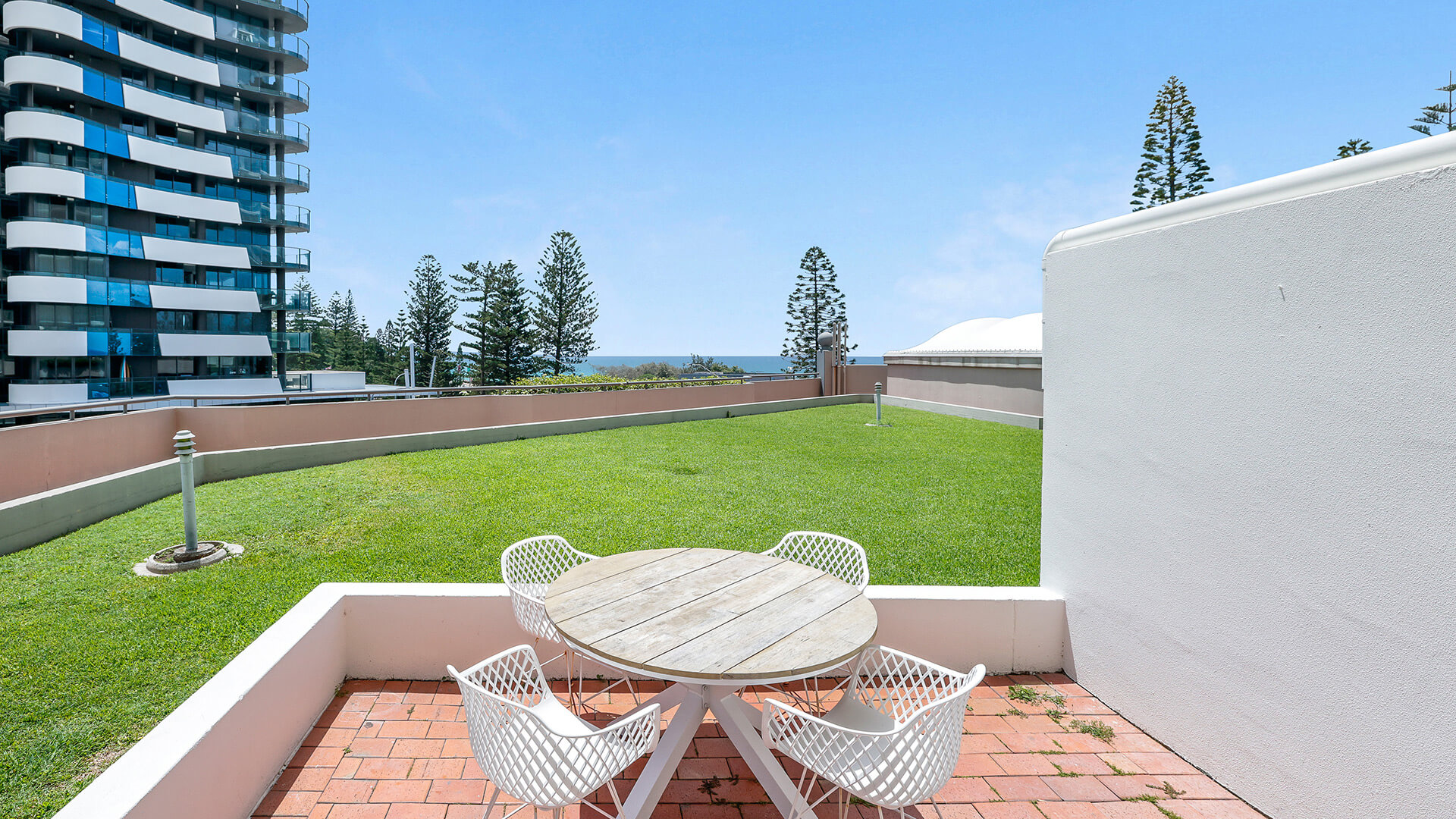 Private courtyard area in the Superior 2 Bedroom Courtyard Apartment at ULTIQA Points North, featuring outdoor seating and partial ocean views.