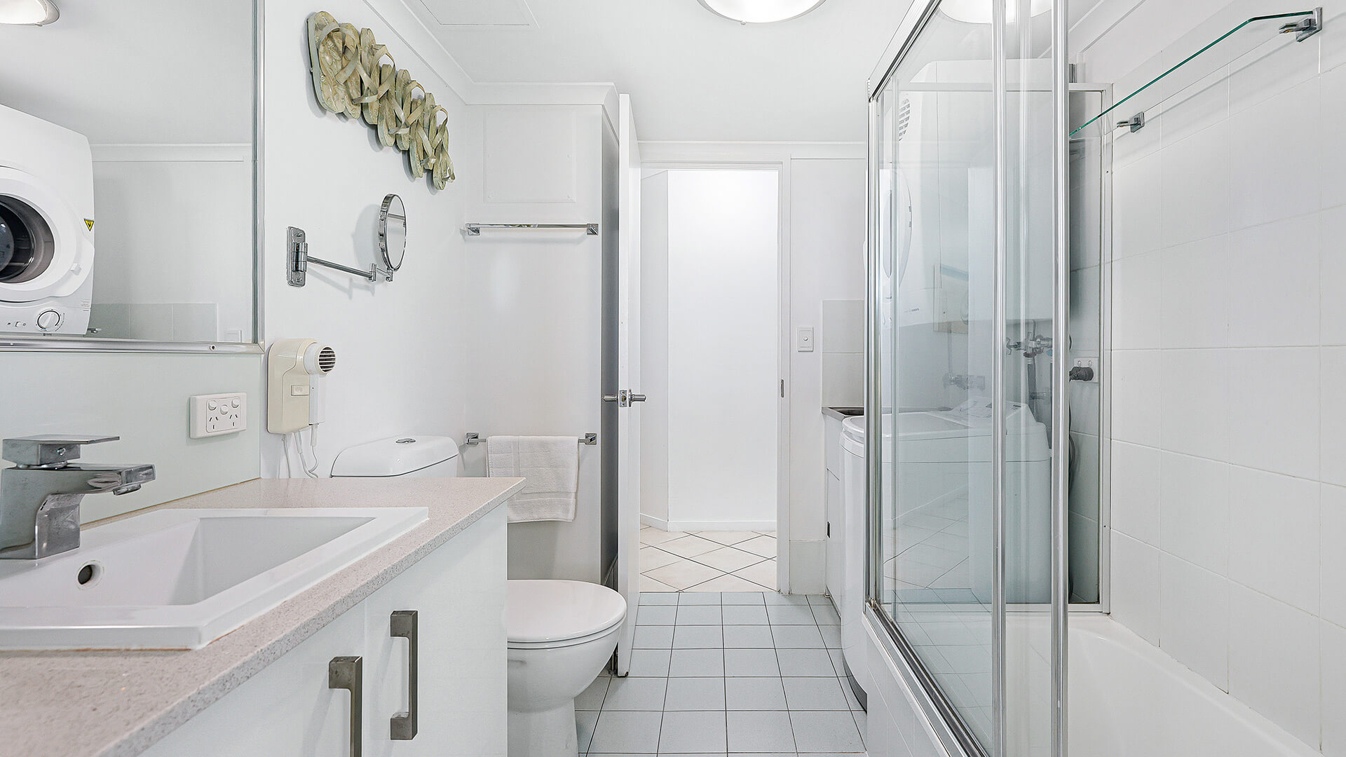 2nd bathroom in a 2 Bedroom Superior Ocean View Apartment featuring vanity, toilet, shower-over-bath, in-room laundry with washer & dryer.