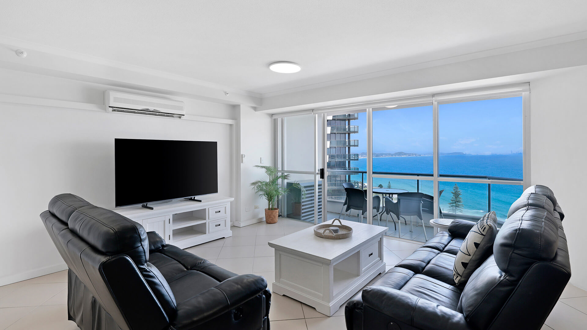 Living area of the 2 Bedroom Superior Ocean View Apartment with leather lounges, coastal décor, and balcony seating overlooking the ocean.