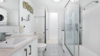 2nd bathroom in a 2 Bedroom Superior Ocean View Apartment with vanity, toilet, shower-over-bath with glass screens, in-room laundry, washer & dryer.