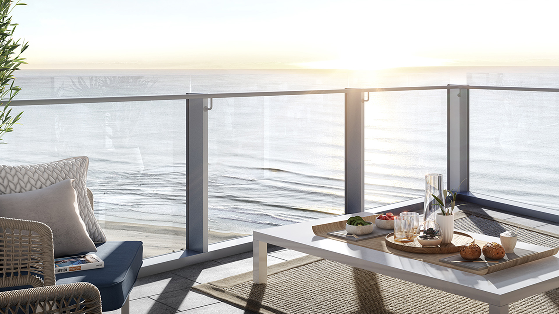 Private balcony at ULTIQA Signature at Broadbeach with ocean views at sunrise, featuring outdoor seating and a table set with breakfast.