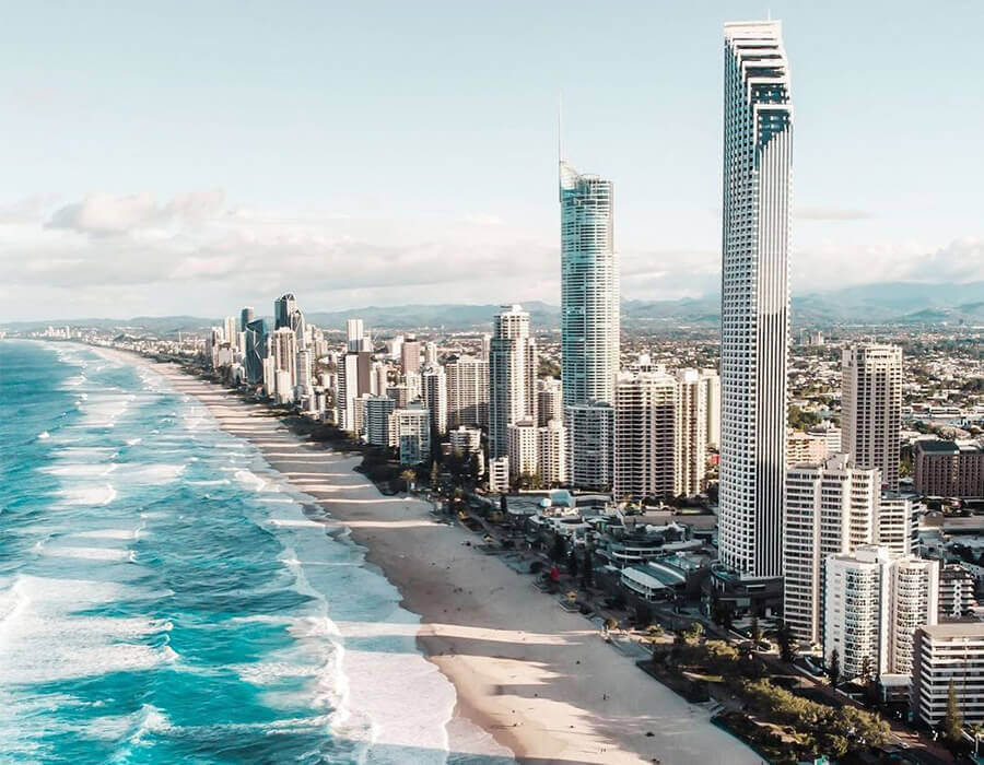 Aerial view of Surfers Paradise skyline with tall beachfront towers and waves along the Gold Coast, Queensland.