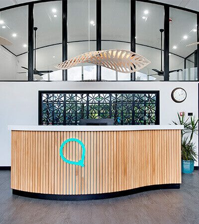 Reception area at ULTIQA Fiji Palms Beach Resort with modern wooden desk, decorative lighting, and large windows.